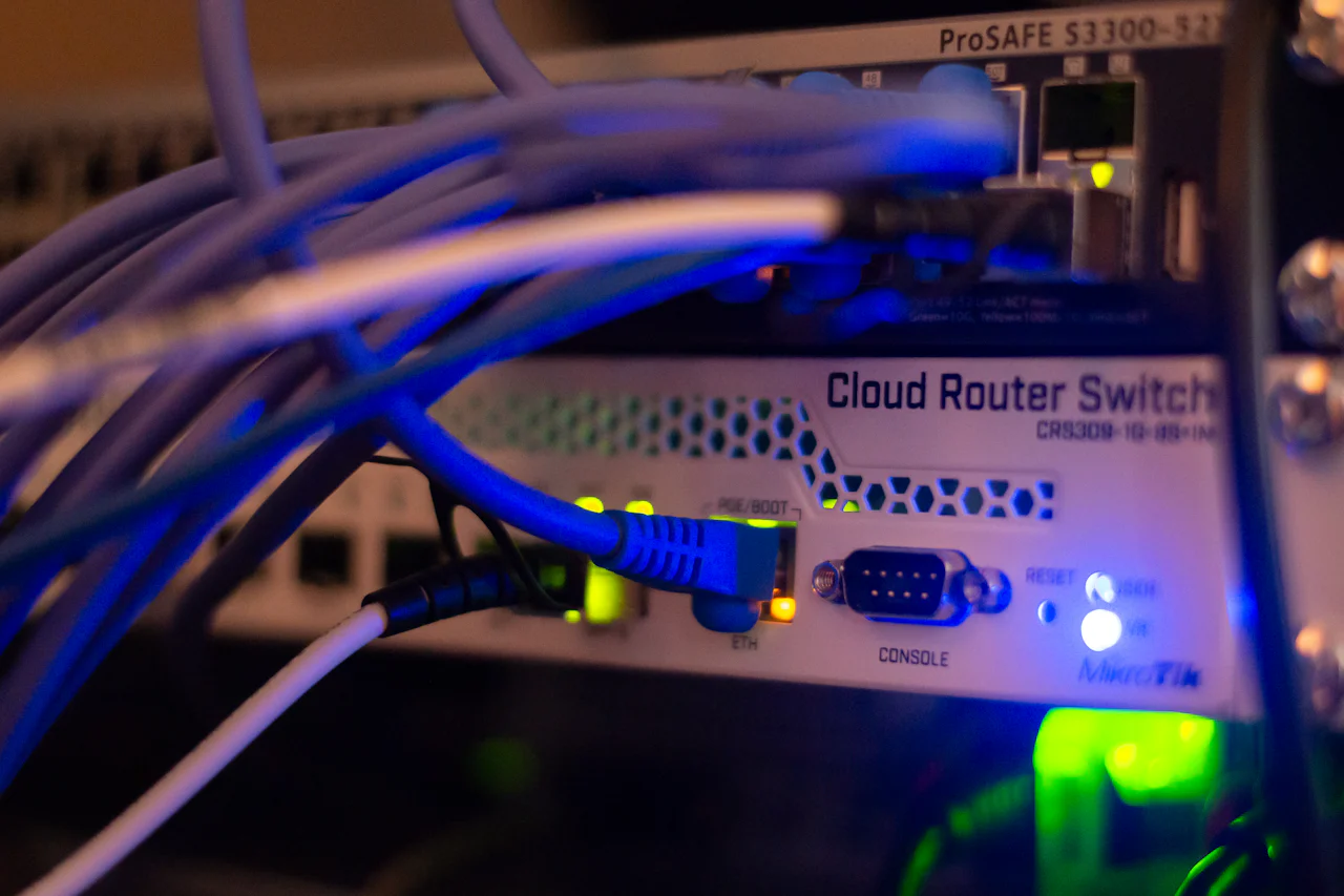 Router dan switch di rak jaringan dengan koneksi kabel Ethernet serta indikator LED